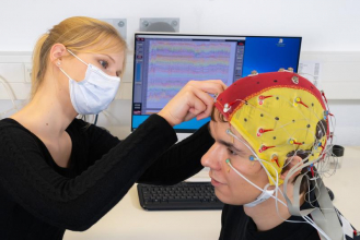 Doktorandin Celina von Eiff befestigt Elektroden an einer Kappe, die der Proband Lucas Riedel währen ... Foto: Jens Meyer/Uni Jena
